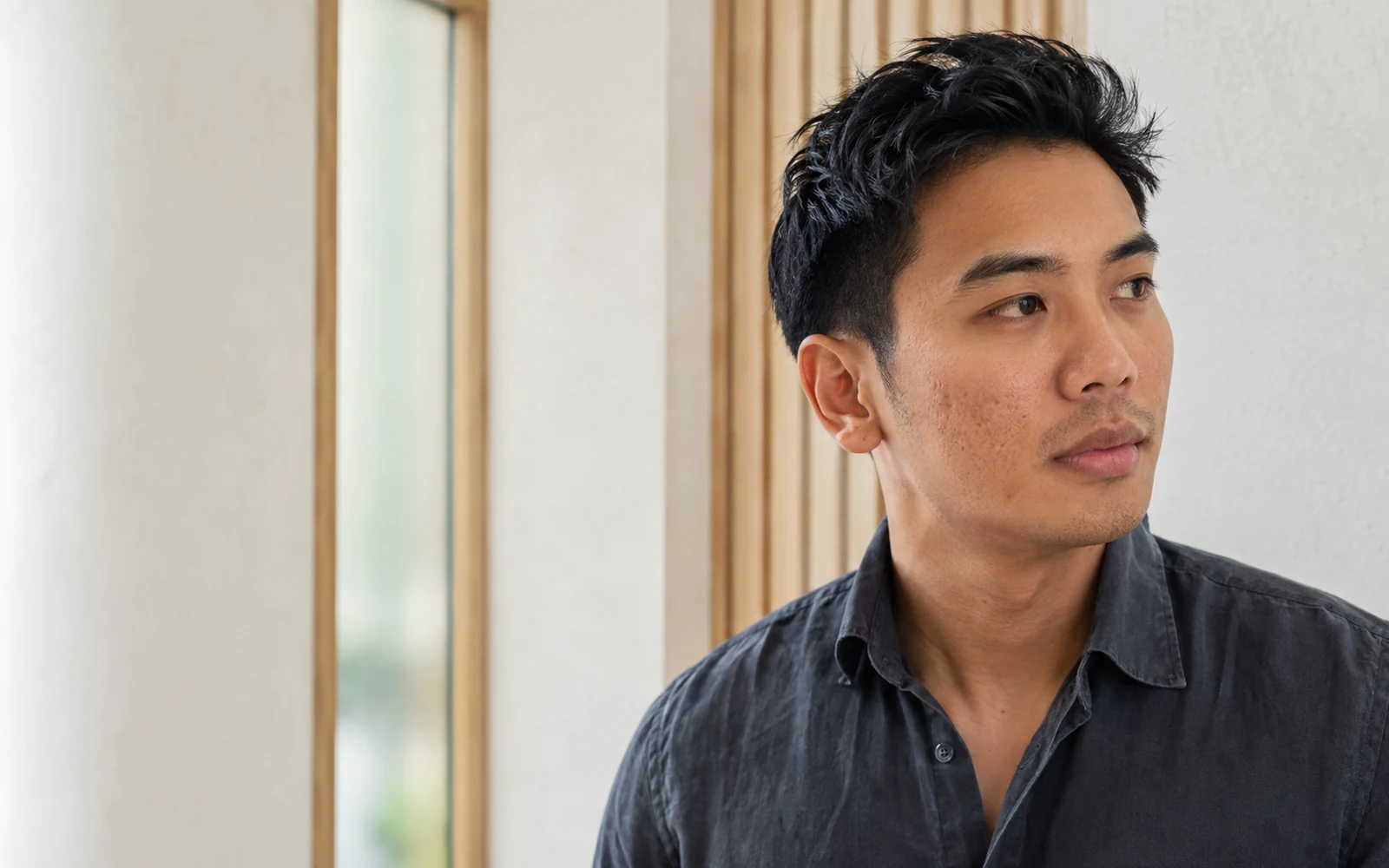 Illustrative portrait of an adult man with natural cheek texture in a charcoal linen shirt