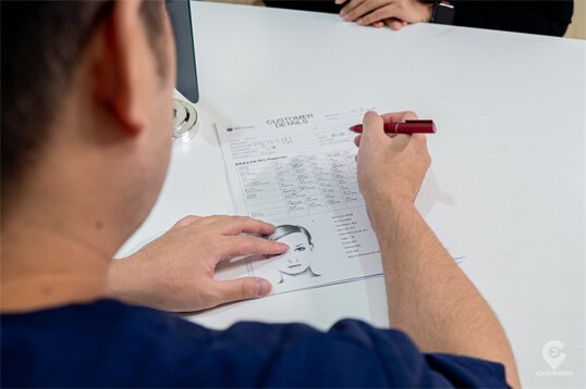 Dr. Kevin Lee carefully documenting patient assessment and creating customized aesthetic treatment plans at Medi Clinic Johor Bahru